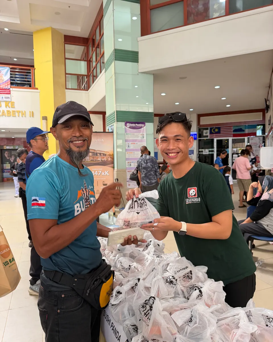 A Sushi Panda crew member hands a Care Box to a visitor at the World Blood Donor Day campaign, Hospital Queen Elizabeth II